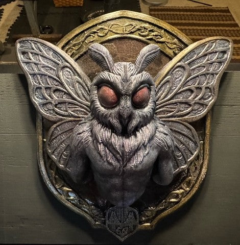 Front view of Mothman wall plaque with red-toned eyes and patterned wings