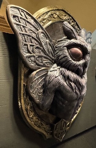 Opposite side view of Mothman plaque with metallic highlights