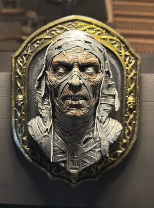 Front view of Mummy bust wall plaque in ornate skull-accented frame