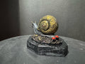 Forest Guardian Snail - front view showing golden filigree shell and dark armored body