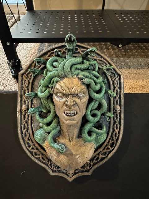 Front view of Medusa relief with green serpents and ornate skull-accented frame