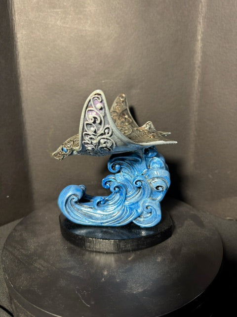 Filigree manta ray statue side view — sculpted wave and black plinth base