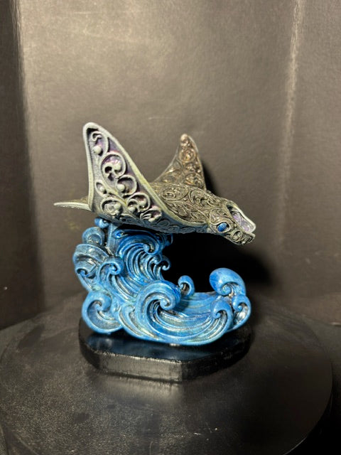 Filigree manta ray statue front view — silver-tone filigree wings over cobalt wave base