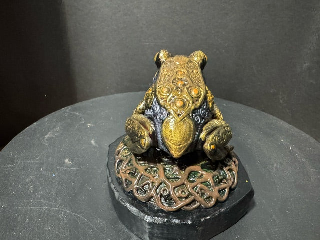 Forest Guardian Frog - three-quarter front view showing amber dome eyes and gold knotwork